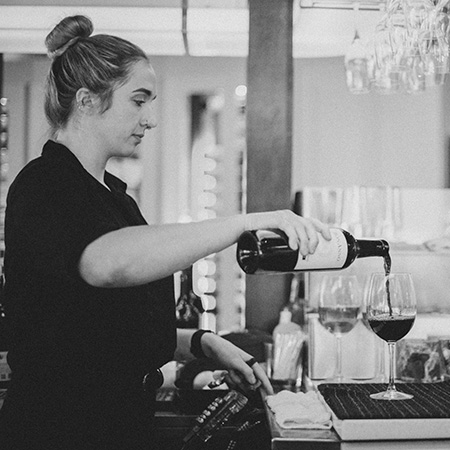 A bartender at Martini Modern Italian pours a glass of wine.